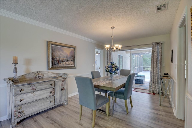 13006 Pebble Beach Cir, Hudson, FL 34667 - dining area with a textured ceiling, a chandelier, light wood-style flooring, and crown molding