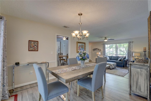 13006 Pebble Beach Cir, Hudson, FL 34667 - dining room featuring a ceiling fan, a textured ceiling, a chandelier, and light wood finished floors
