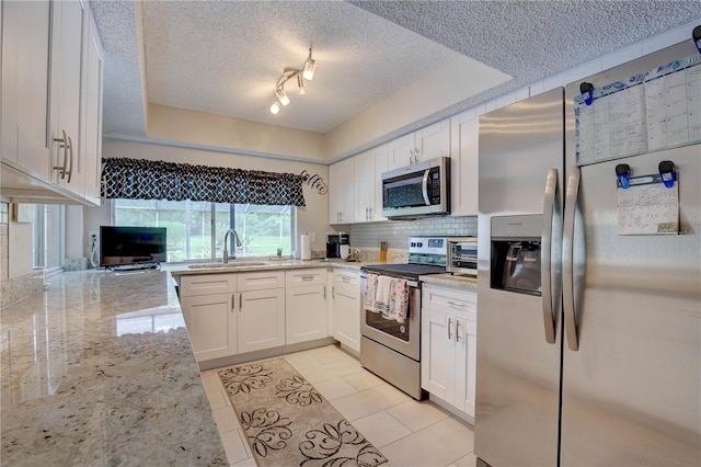 13006 Pebble Beach Cir, Hudson, FL 34667 - kitchen with appliances with stainless steel finishes, a textured ceiling, white cabinets, backsplash, and light stone counters