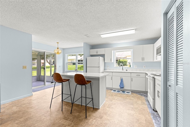 9664 SW 94th Ter Unit A, Ocala, FL 34481 - kitchen with white appliances, a kitchen island, a breakfast bar area, white cabinets, and healthy amount of natural light