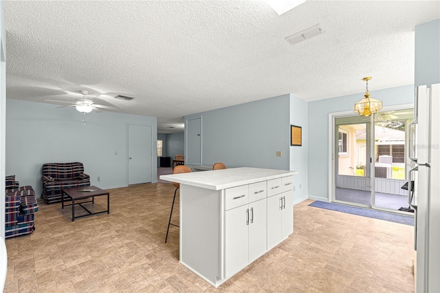 9664 SW 94th Ter Unit A, Ocala, FL 34481 - kitchen featuring light countertops, a textured ceiling, a kitchen breakfast bar, freestanding refrigerator, and white cabinets