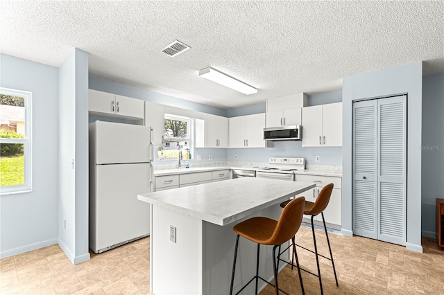 9664 SW 94th Ter Unit A, Ocala, FL 34481 - kitchen featuring white appliances, light countertops, a kitchen bar, a center island, and white cabinetry