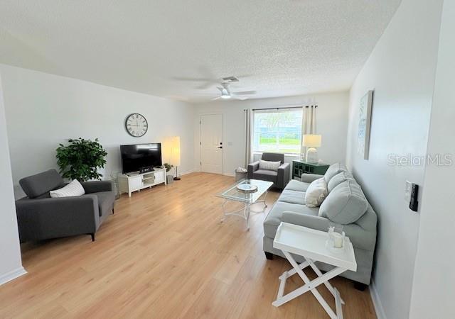 528 Valencia Pl, Lady Lake, FL 32159 - living area with light wood-type flooring, ceiling fan, and a textured ceiling