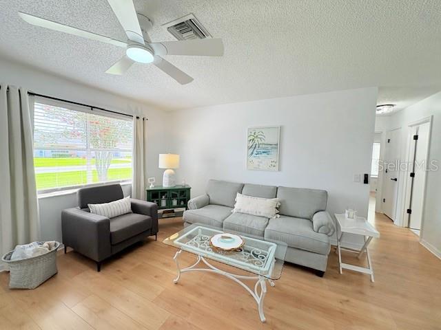 528 Valencia Pl, Lady Lake, FL 32159 - living room featuring light wood-type flooring, a textured ceiling, and a ceiling fan