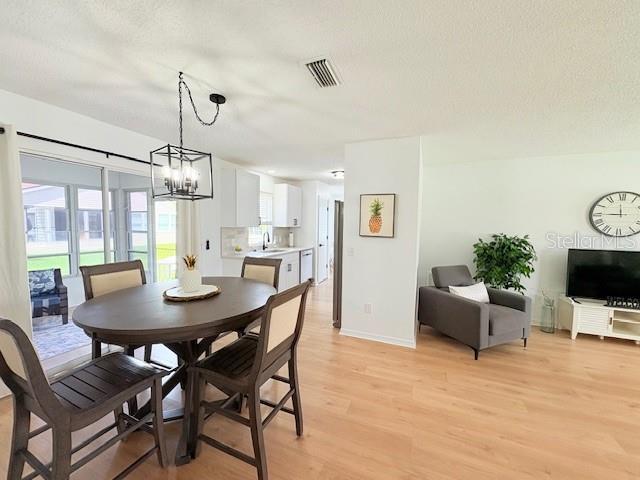 528 Valencia Pl, Lady Lake, FL 32159 - dining space featuring light wood finished floors and a chandelier