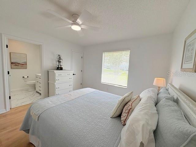 528 Valencia Pl, Lady Lake, FL 32159 - bedroom featuring light wood finished floors, ensuite bathroom, a ceiling fan, and a textured ceiling