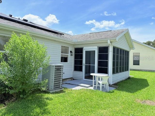 528 Valencia Pl, Lady Lake, FL 32159 - rear view of property with a sunroom, a lawn, and roof with shingles