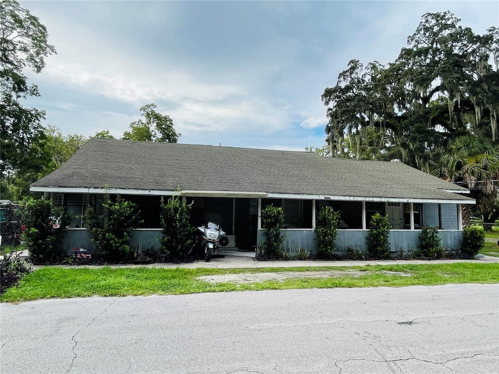 805 NW 24th Pl, Ocala, FL 34475 - single story home featuring a carport, driveway, a sunroom, and roof with shingles