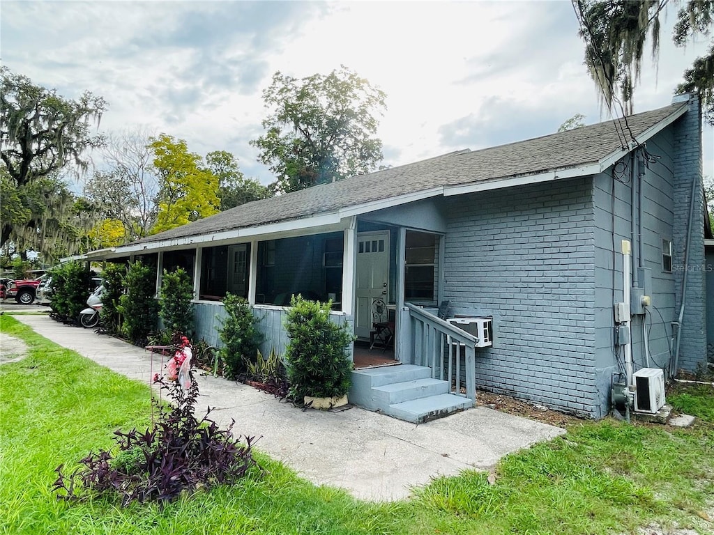 805 NW 24th Pl, Ocala, FL 34475 - rear view of house featuring brick siding, a lawn, and a sunroom