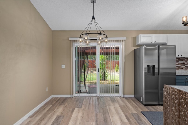 3224 E Davis Ln Unit 29, Inverness, FL 34453 - unfurnished dining area with a chandelier, light wood-style flooring, and a textured ceiling