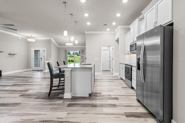 837 E Epsom Ct, Hernando, FL 34442 - kitchen with appliances with stainless steel finishes, crown molding, a kitchen island with sink, white cabinets, and light wood-style flooring