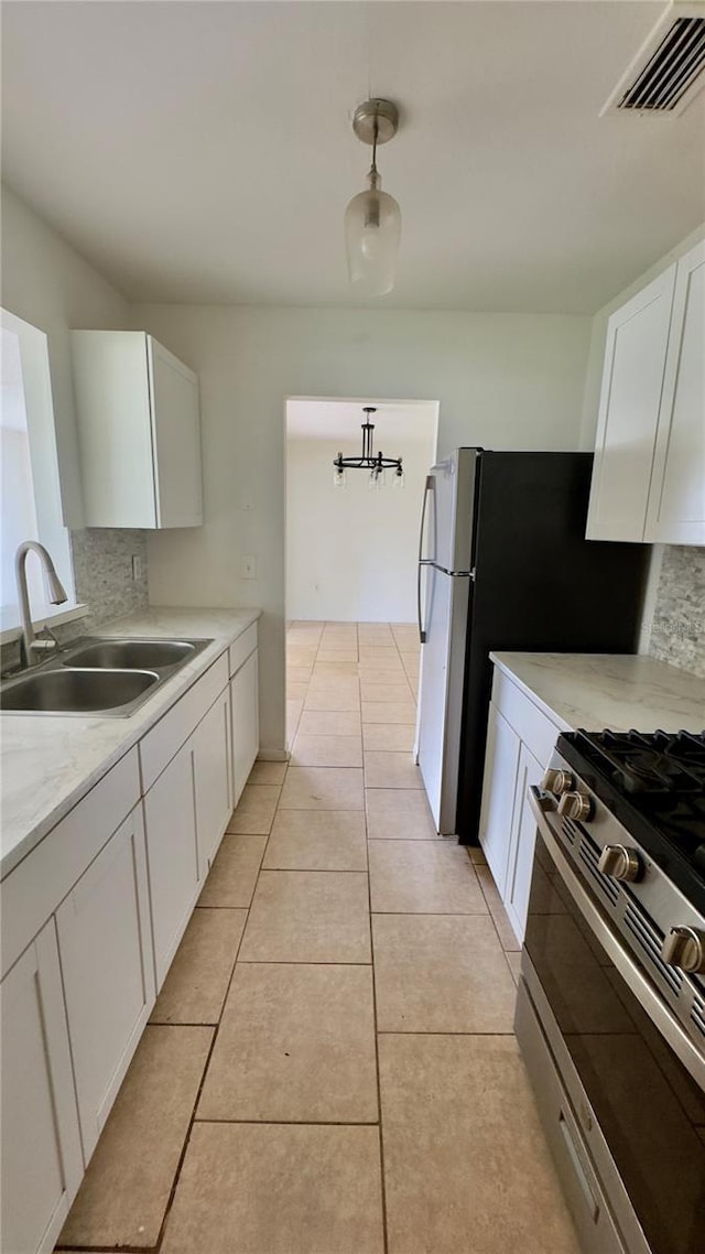 15091 SW 35th Cir, Ocala, FL 34473 - kitchen with stainless steel gas stove, white cabinetry, light countertops, tasteful backsplash, and hanging light fixtures