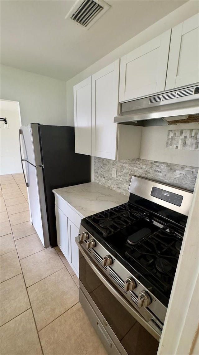 15091 SW 35th Cir, Ocala, FL 34473 - kitchen featuring stainless steel gas range oven, under cabinet range hood, backsplash, white cabinetry, and light tile patterned floors