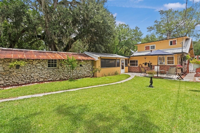 11 62nd St, Yankeetown, FL 34498 - rear view of property with a patio, a lawn, stone siding, and a metal roof