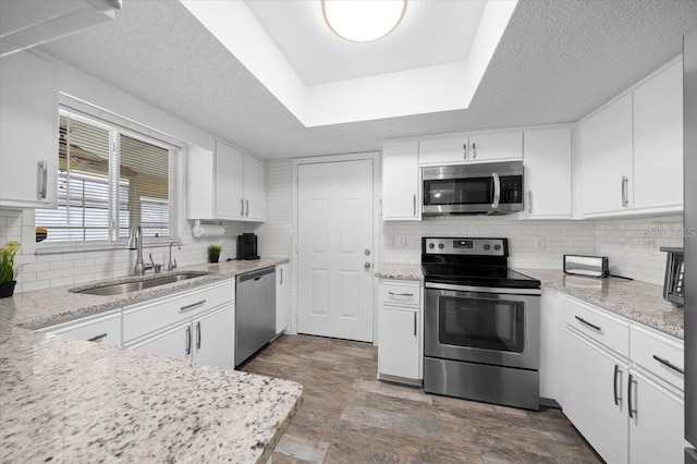 10492 SE 178th St, Summerfield, FL 34491 - kitchen featuring stainless steel appliances, decorative backsplash, white cabinetry, light stone countertops, and a textured ceiling