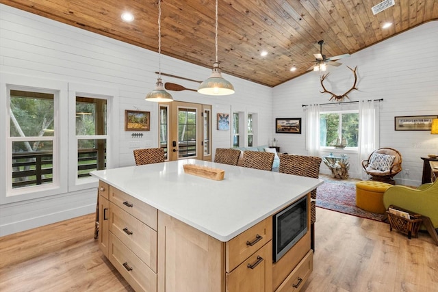 5328 Riverside Dr, Yankeetown, FL 34498 - kitchen with stainless steel microwave, vaulted ceiling, open floor plan, light wood-style flooring, and a ceiling fan