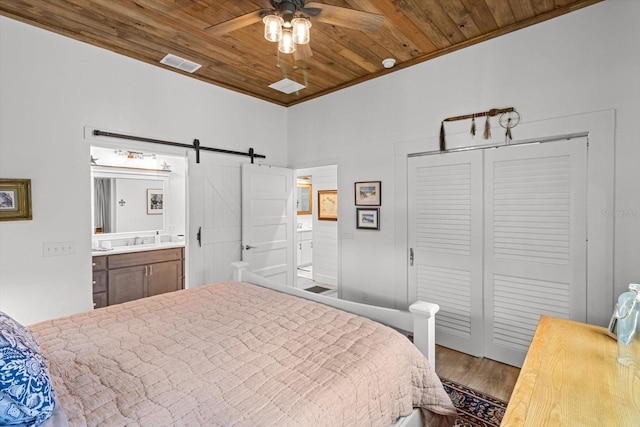 5328 Riverside Dr, Yankeetown, FL 34498 - bedroom with a barn door, wooden ceiling, wood finished floors, a closet, and ensuite bathroom