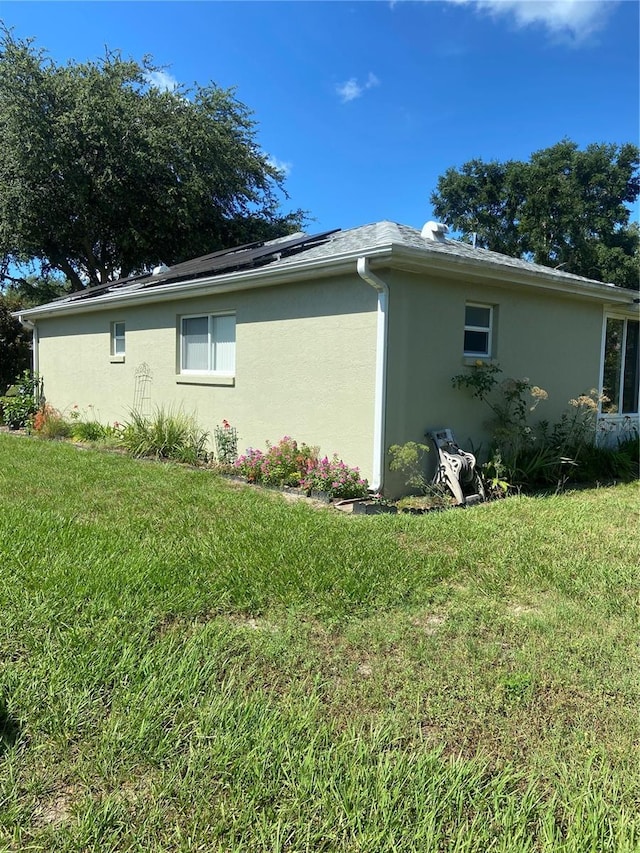 9771 SW 97th Ln, Ocala, FL 34481 - view of side of home featuring stucco siding, roof mounted solar panels, and a yard