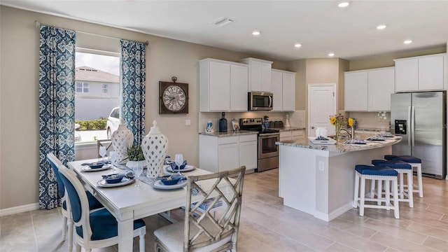 4253 SW 54th Street Rd, Ocala, FL 34474 - kitchen with appliances with stainless steel finishes, a kitchen bar, decorative backsplash, a kitchen island with sink, and white cabinetry