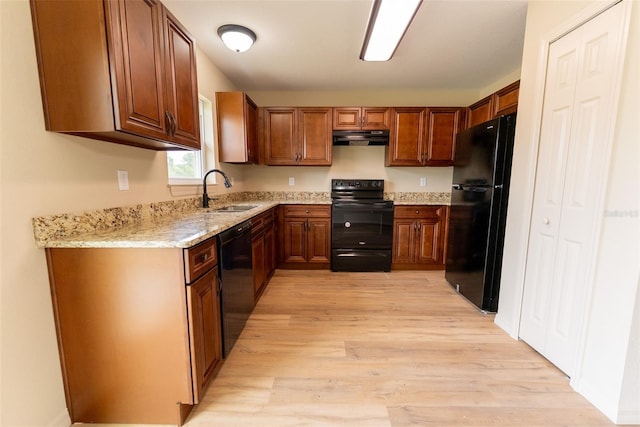 21 Locust Loop Radl, Ocala, FL 34472 - kitchen featuring black appliances, under cabinet range hood, light wood-style flooring, light stone countertops, and brown cabinets