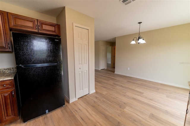 21 Locust Loop Radl, Ocala, FL 34472 - kitchen featuring freestanding refrigerator, light wood-type flooring, a chandelier, hanging light fixtures, and brown cabinets