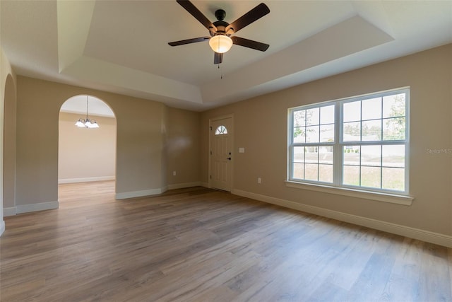 45 Pecan Course Loop, Ocala, FL 34472 - empty room featuring a raised ceiling, arched walkways, ceiling fan, light wood-style flooring, and a chandelier