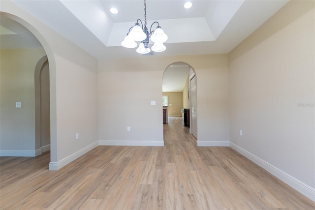 45 Pecan Course Loop, Ocala, FL 34472 - unfurnished room with a tray ceiling, light wood-type flooring, a chandelier, and arched walkways