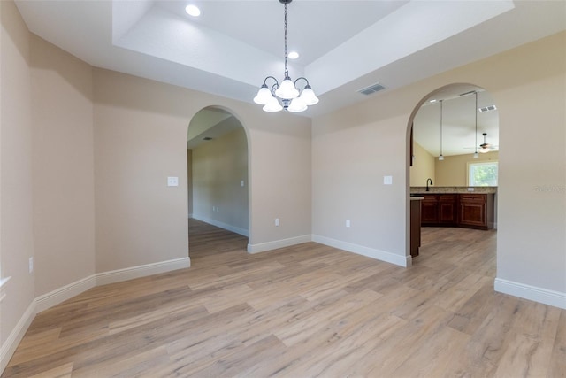 45 Pecan Course Loop, Ocala, FL 34472 - empty room featuring arched walkways, a tray ceiling, a chandelier, light wood-style floors, and recessed lighting