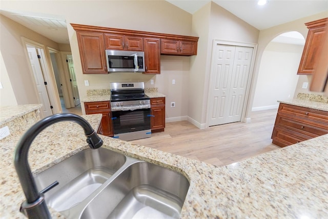 45 Pecan Course Loop, Ocala, FL 34472 - kitchen with appliances with stainless steel finishes, light wood-type flooring, light stone counters, arched walkways, and vaulted ceiling