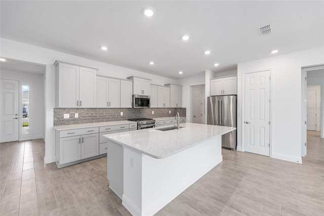 10880 SW 101st Loop, Ocala, FL 34481 - kitchen with high quality appliances, a center island with sink, tasteful backsplash, light stone countertops, and light wood finished floors