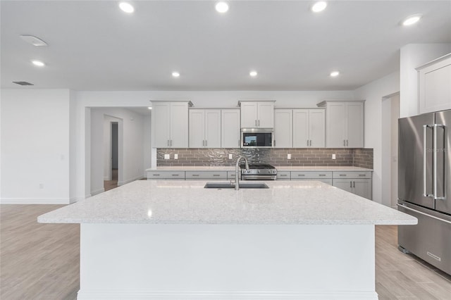 10880 SW 101st Loop, Ocala, FL 34481 - kitchen featuring appliances with stainless steel finishes, a center island with sink, tasteful backsplash, light stone countertops, and recessed lighting