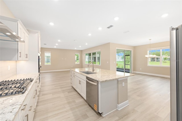10833 SW 101st Loop, Ocala, FL 34481 - kitchen featuring stainless steel appliances, wall chimney exhaust hood, open floor plan, light wood-type flooring, and an island with sink