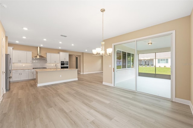 10833 SW 101st Loop, Ocala, FL 34481 - kitchen featuring wall chimney range hood, freestanding refrigerator, a chandelier, decorative backsplash, and light wood-style floors