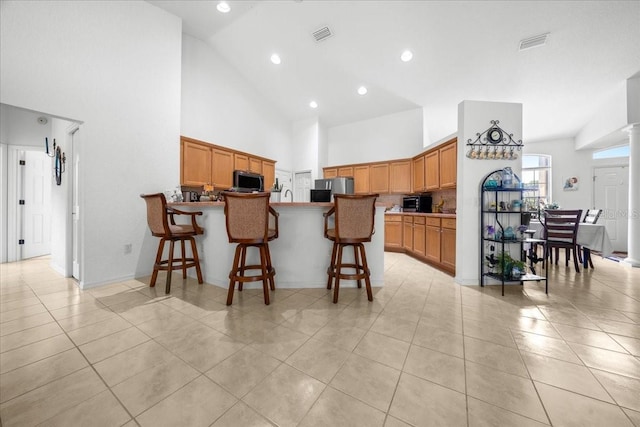 19583 SW 77th Loop, Dunnellon, FL 34432 - kitchen featuring high vaulted ceiling, appliances with stainless steel finishes, light tile patterned flooring, a peninsula, and a breakfast bar