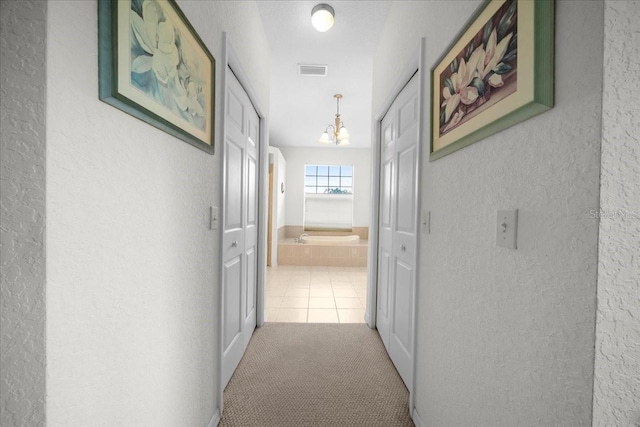 19583 SW 77th Loop, Dunnellon, FL 34432 - hall with a textured wall, a chandelier, carpet flooring, and tile patterned floors