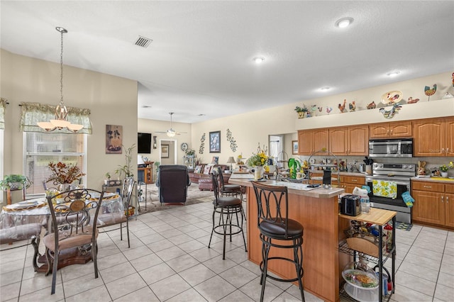 2587 W Angola Dr, Beverly Hills, FL 34465 - kitchen featuring appliances with stainless steel finishes, light countertops, light tile patterned floors, a breakfast bar, and open floor plan