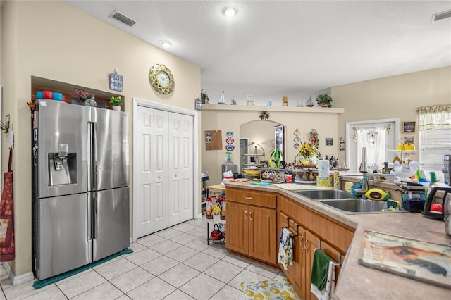 2587 W Angola Dr, Beverly Hills, FL 34465 - kitchen featuring stainless steel refrigerator with ice dispenser, light countertops, light tile patterned floors, brown cabinets, and arched walkways