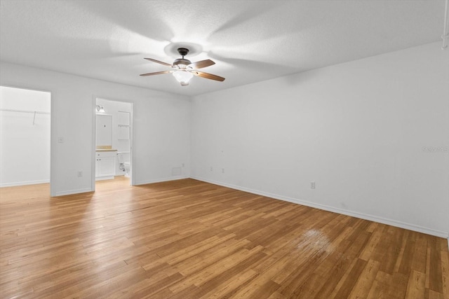 2105 E Dearborn Dr, Hernando, FL 34442 - unfurnished bedroom with a walk in closet, light wood finished floors, ensuite bathroom, a ceiling fan, and a textured ceiling
