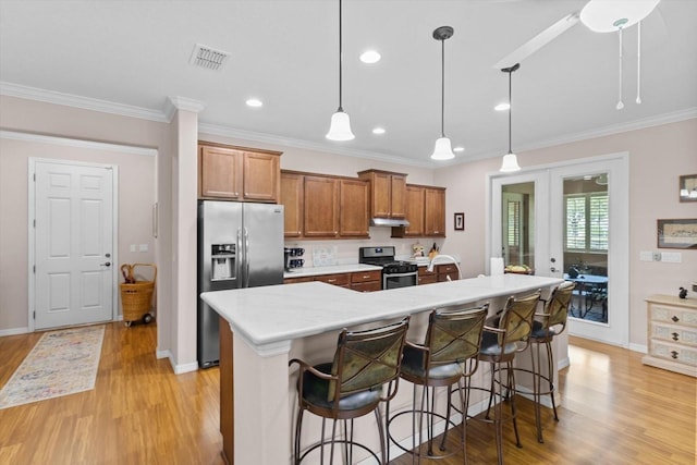 9251 SW 94th Loop, Ocala, FL 34481 - kitchen with stainless steel appliances, light wood-type flooring, brown cabinets, ornamental molding, and light countertops