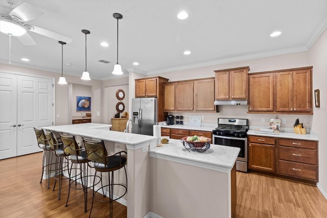 9251 SW 94th Loop, Ocala, FL 34481 - kitchen featuring appliances with stainless steel finishes, brown cabinetry, light wood-style flooring, a kitchen island with sink, and light countertops