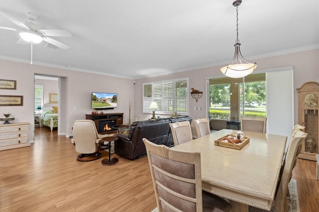 9251 SW 94th Loop, Ocala, FL 34481 - dining space with light wood-style flooring, crown molding, a warm lit fireplace, and ceiling fan