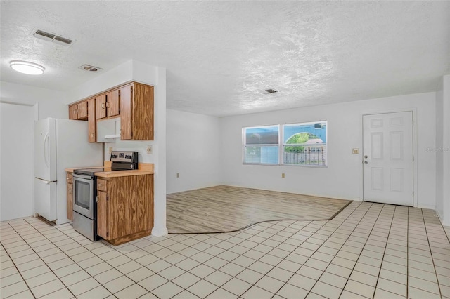231 S Barbour St, Beverly Hills, FL 34465 - kitchen with electric stove, a textured ceiling, light countertops, brown cabinets, and freestanding refrigerator
