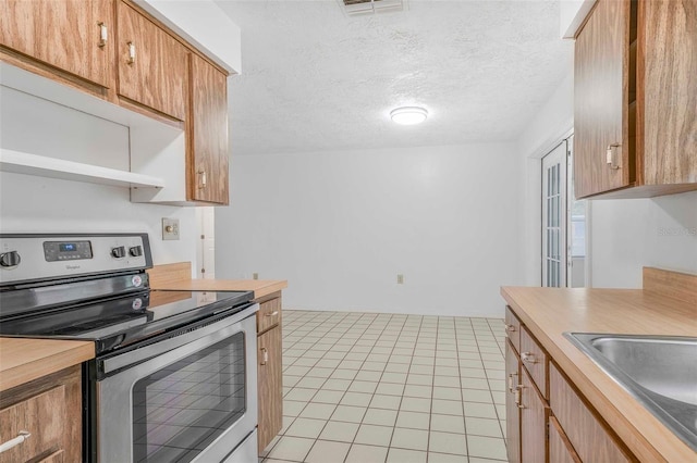 231 S Barbour St, Beverly Hills, FL 34465 - kitchen with stainless steel electric stove, open shelves, light tile patterned floors, and a textured ceiling