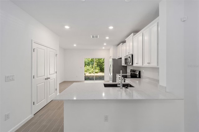 3409 SW 34th Ave Circle Unit 5, Ocala, FL 34474 - kitchen featuring appliances with stainless steel finishes, white cabinetry, light wood finished floors, light stone counters, and recessed lighting