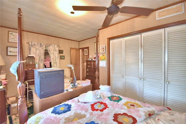 bedroom with wooden walls, a closet, ceiling fan, and crown molding