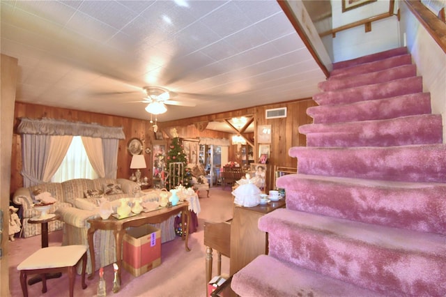 living room with carpet, ceiling fan, and wood walls