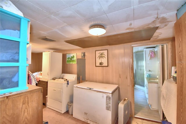 laundry room with washing machine and clothes dryer and wooden walls