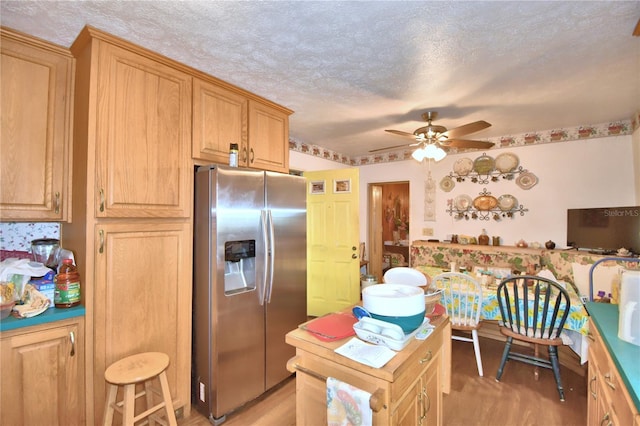 kitchen with stainless steel fridge with ice dispenser, a textured ceiling, ceiling fan, and light brown cabinetry