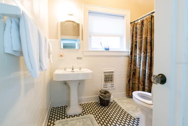 bathroom featuring toilet, tile flooring, and tile walls