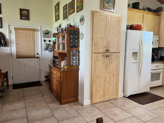 kitchen featuring white appliances, light tile patterned floors, and light brown cabinets